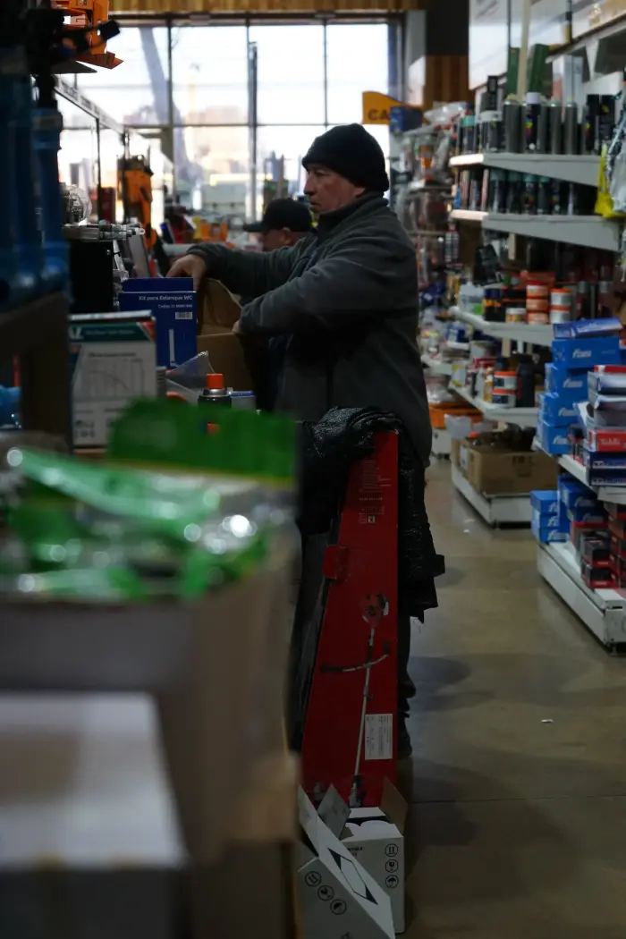 Un vendedor de Ferretería Buenos Aires atendiendo detrás del mesón, entre los estantes del local